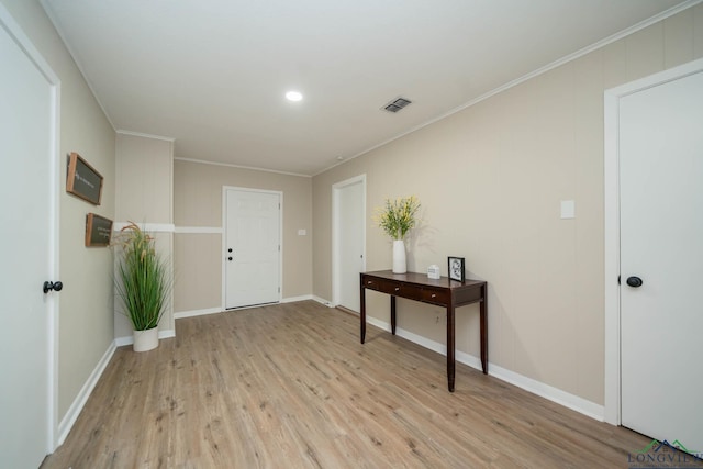 foyer entrance featuring crown molding and light hardwood / wood-style floors