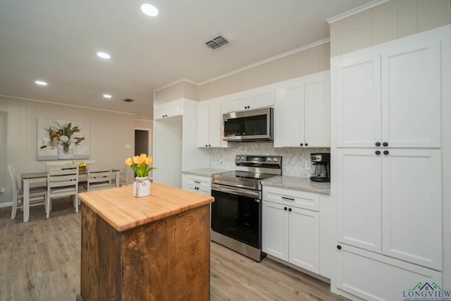 kitchen with light wood-type flooring, ornamental molding, white cabinets, and appliances with stainless steel finishes