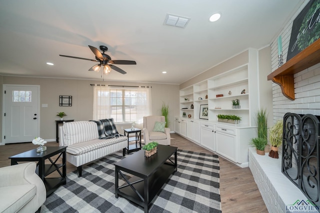 living room with a fireplace, light hardwood / wood-style flooring, and ceiling fan