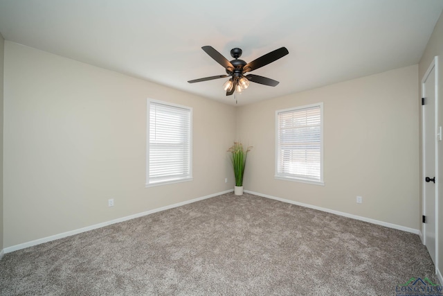 carpeted spare room featuring a wealth of natural light and ceiling fan