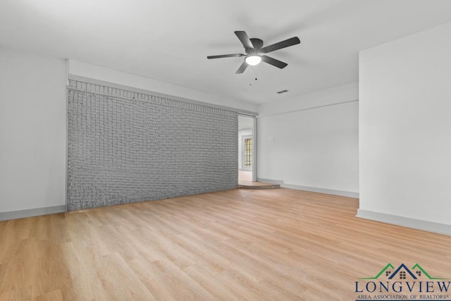 unfurnished room with ceiling fan, brick wall, and light hardwood / wood-style flooring