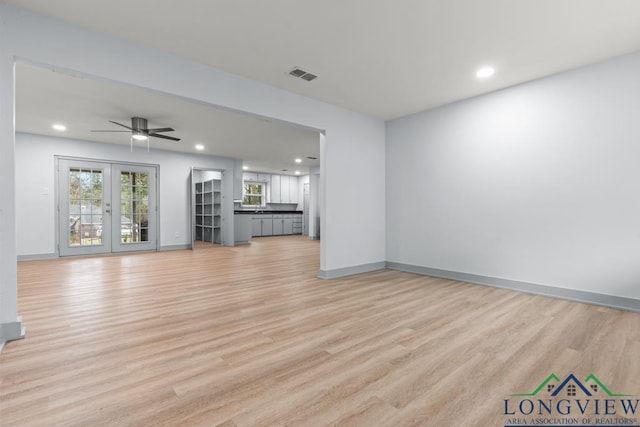 unfurnished living room featuring french doors, ceiling fan, and light hardwood / wood-style flooring