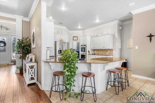 1900 Frostwood Dr, Tyler, TX 75703 - kitchen featuring a kitchen breakfast bar, a peninsula, appliances with stainless steel finishes, and dark stone counters