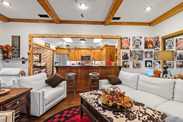 living room featuring beamed ceiling, dark hardwood / wood-style flooring, sink, and a skylight