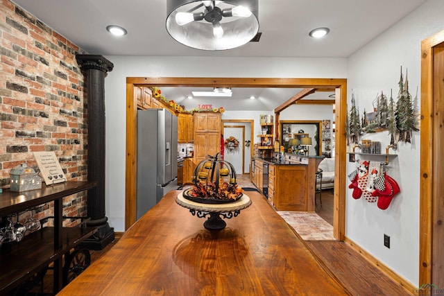 dining space with light wood-type flooring, sink, and brick wall