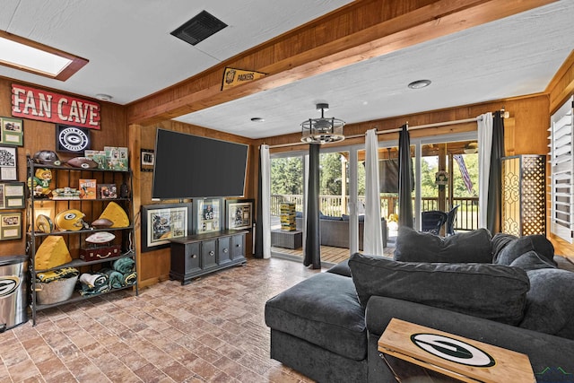 living room with a skylight, crown molding, and wooden walls