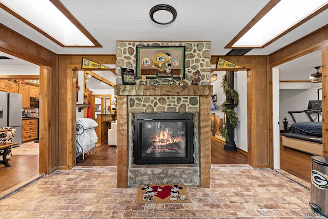 living room with a stone fireplace and wooden walls