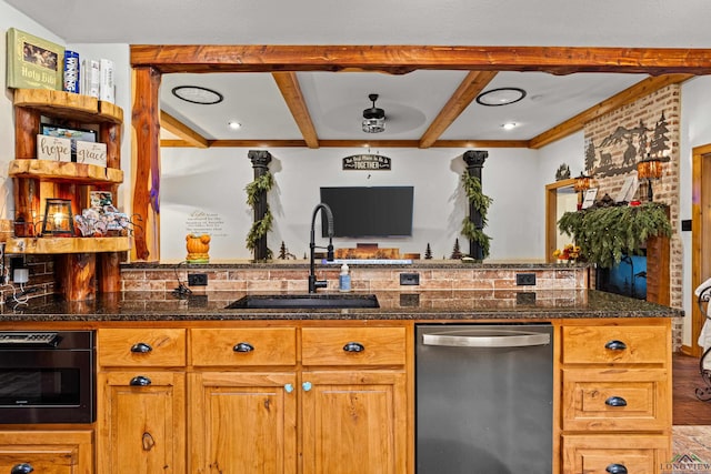 kitchen with stainless steel dishwasher, dark stone counters, and sink