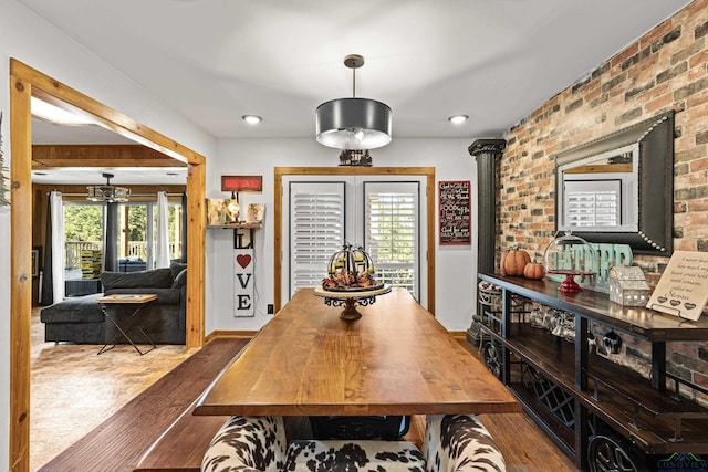 dining area featuring hardwood / wood-style floors and brick wall