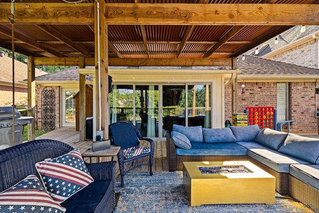 view of patio / terrace featuring a wooden deck, a grill, and an outdoor living space with a fire pit