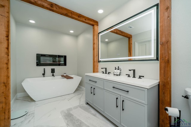 full bathroom featuring a sink, a freestanding tub, marble finish floor, and recessed lighting