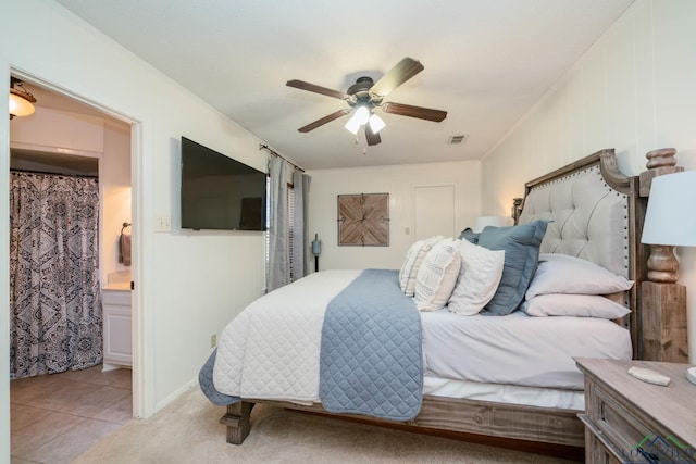 bedroom with ensuite bath, tile patterned floors, and a ceiling fan