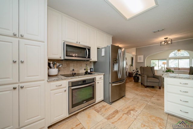 kitchen with open floor plan, decorative backsplash, stainless steel appliances, arched walkways, and white cabinetry