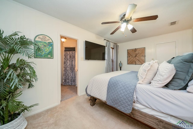 bedroom with ceiling fan, visible vents, ensuite bathroom, and light carpet