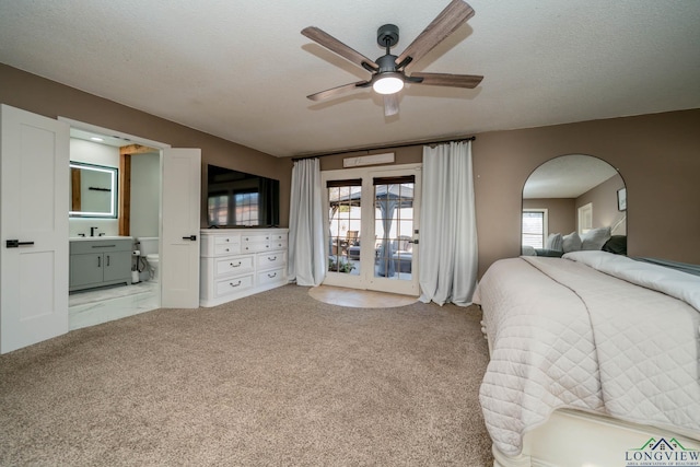 bedroom featuring multiple windows, ensuite bathroom, carpet floors, and a textured ceiling