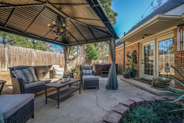 view of patio featuring a gazebo, an outdoor living space, a hot tub, and fence