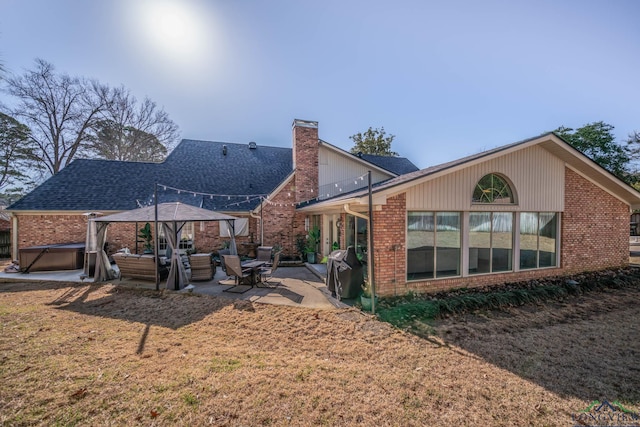 back of property featuring a patio, roof with shingles, a chimney, a gazebo, and brick siding