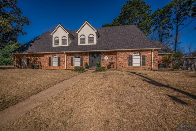 view of front of home with brick siding, a front lawn, and roof with shingles