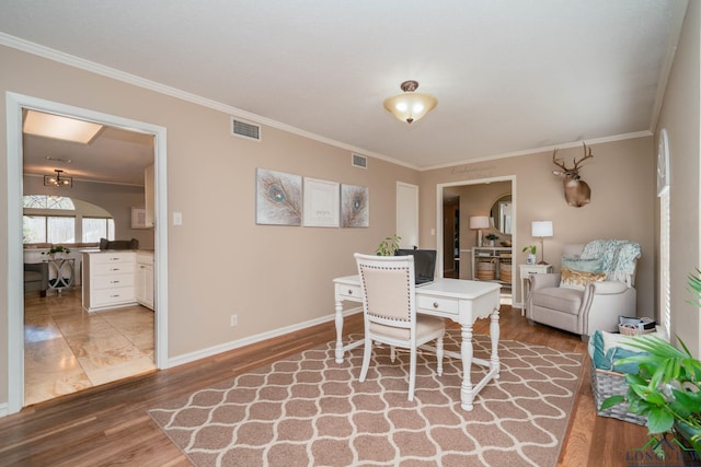 dining room with visible vents, baseboards, wood finished floors, and crown molding