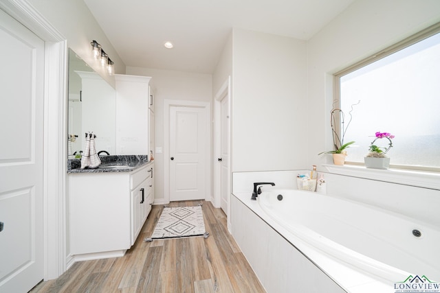 full bathroom with a bath, recessed lighting, vanity, and wood finished floors