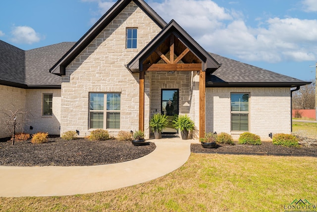 french country inspired facade with a front yard, brick siding, and roof with shingles