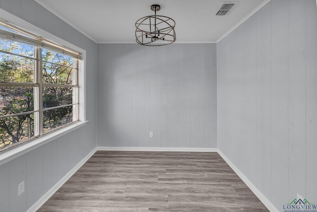 unfurnished dining area with crown molding, wooden walls, and a chandelier