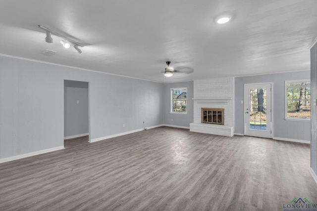 unfurnished living room featuring a fireplace, plenty of natural light, ornamental molding, and ceiling fan