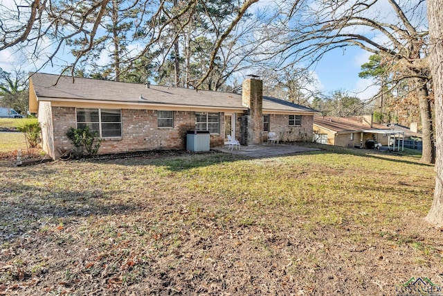 back of property with a patio area, brick siding, a lawn, and a chimney