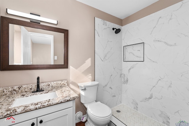 bathroom with vanity, toilet, and a tile shower