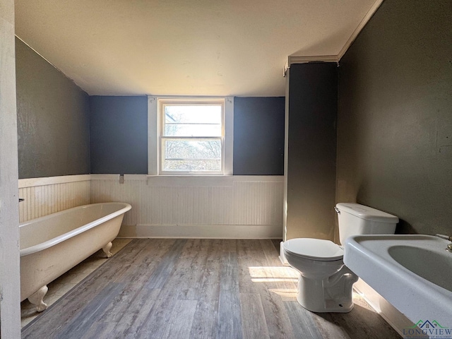 full bathroom with wood finished floors, a freestanding tub, vaulted ceiling, wainscoting, and toilet