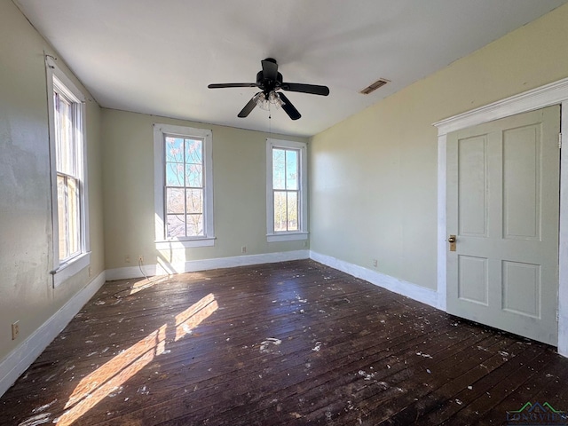 empty room featuring visible vents, a ceiling fan, baseboards, and wood-type flooring