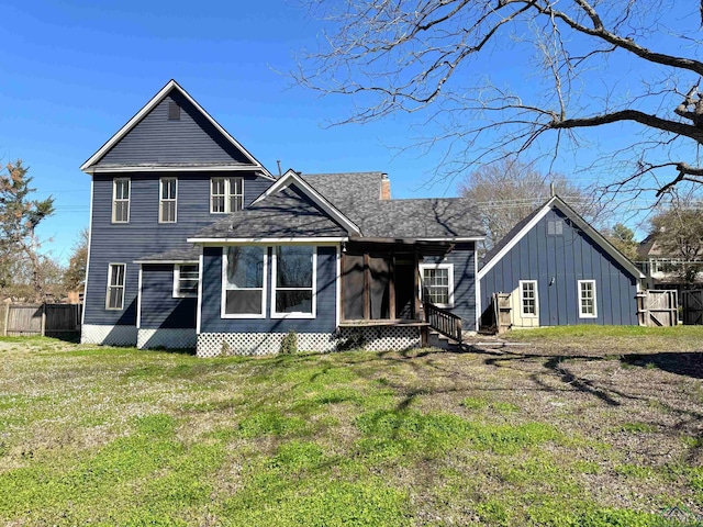 back of house featuring board and batten siding, a chimney, a yard, and a sunroom