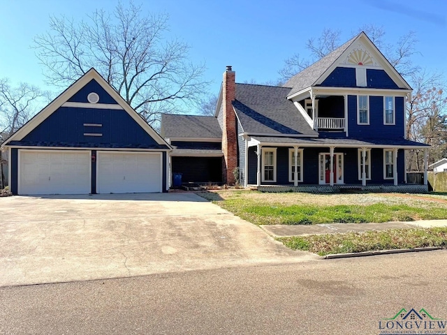 view of front of home featuring a front lawn, covered porch, a chimney, a garage, and driveway