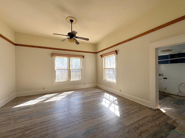 spare room featuring baseboards, dark wood-type flooring, and ceiling fan