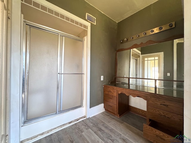 bathroom with a stall shower, visible vents, baseboards, and wood finished floors