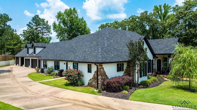 view of front of property featuring roof with shingles, driveway, central AC, and a front lawn