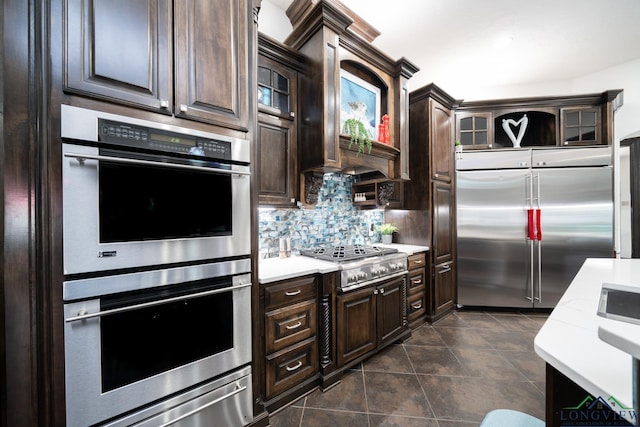 kitchen featuring appliances with stainless steel finishes, light countertops, dark brown cabinetry, and tasteful backsplash