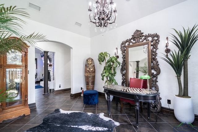 interior space featuring decorative columns, visible vents, arched walkways, baseboards, and a notable chandelier