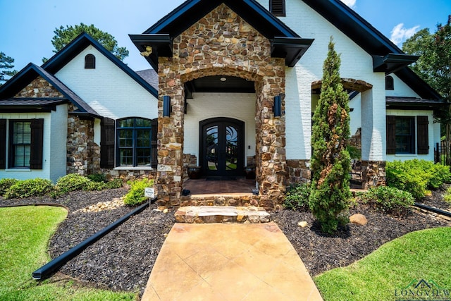 doorway to property featuring stone siding, french doors, and brick siding