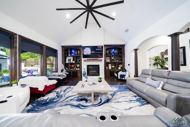 living room featuring decorative columns, visible vents, arched walkways, a stone fireplace, and high vaulted ceiling