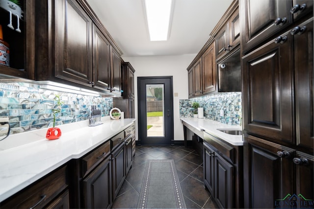 kitchen with dark brown cabinetry, tasteful backsplash, baseboards, and dark tile patterned flooring