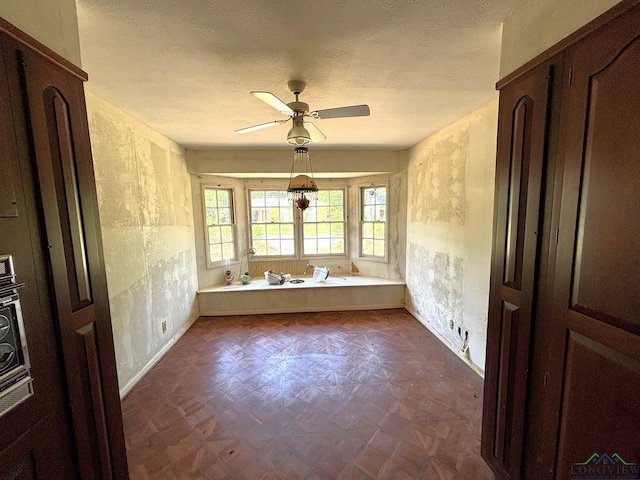 spare room with ceiling fan, dark parquet floors, and a textured ceiling