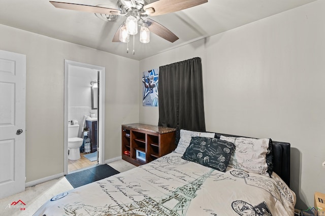 carpeted bedroom with ensuite bath, baseboards, and a ceiling fan