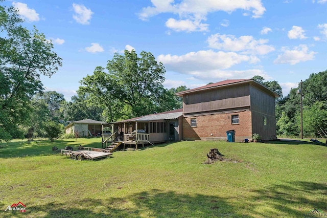 rear view of house featuring a sunroom and a yard