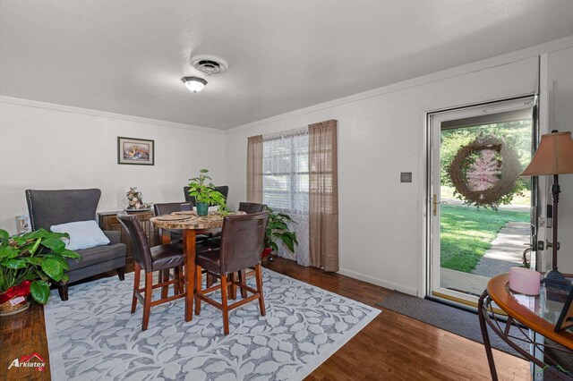 dining room featuring wood finished floors, crown molding, and baseboards