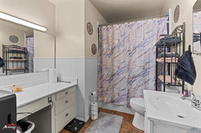 bathroom featuring vanity, toilet, and a wainscoted wall
