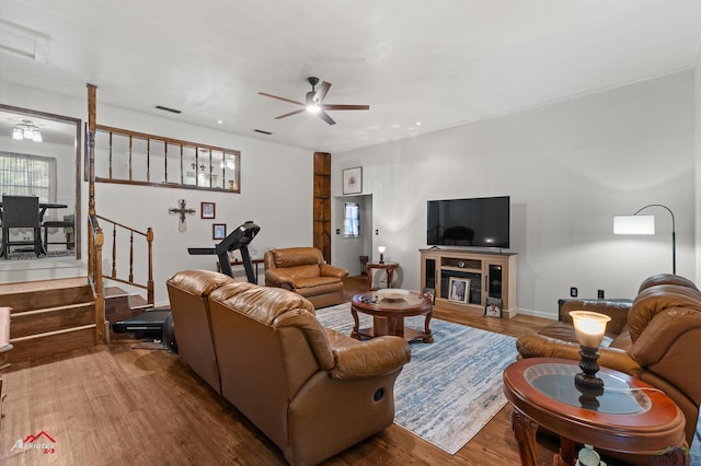 living room featuring wood finished floors, a ceiling fan, stairway, and baseboards