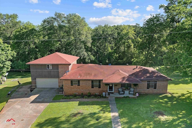 view of front of home with driveway, brick siding, a garage, covered porch, and a view of trees
