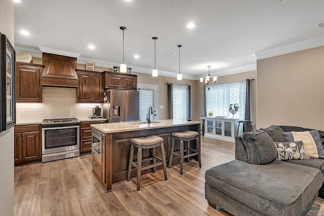 kitchen featuring stainless steel appliances, a sink, open floor plan, custom range hood, and a breakfast bar area