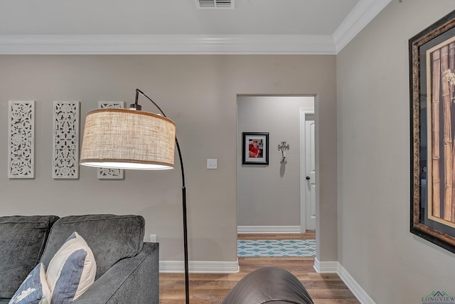sitting room featuring visible vents, baseboards, wood finished floors, and crown molding